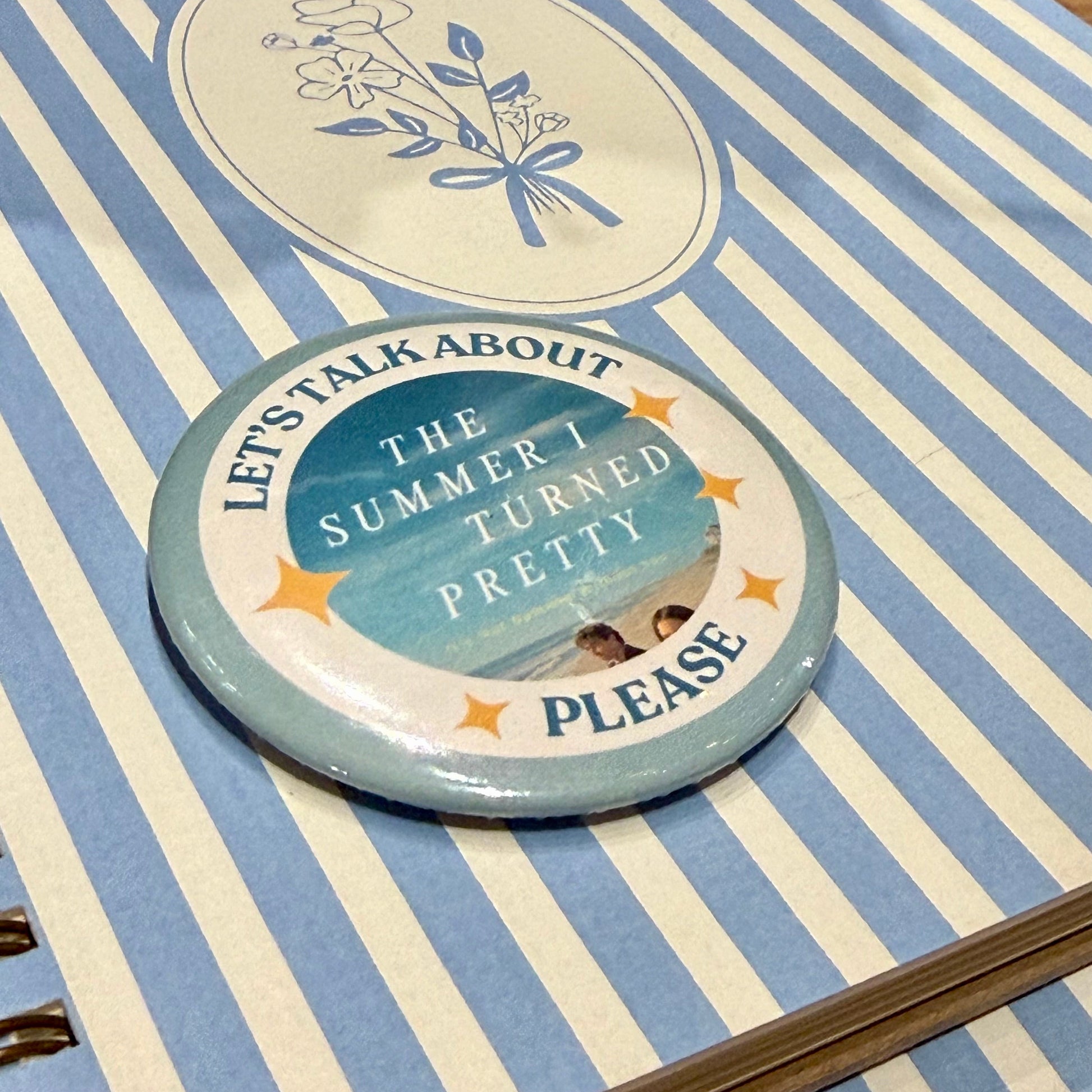 Decorative button with text and design on a striped surface