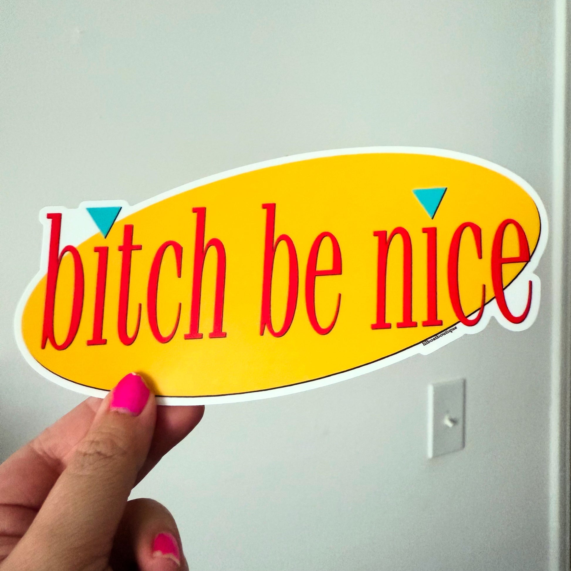 Sticker with 'bitch be nice' text held by a hand against a white background