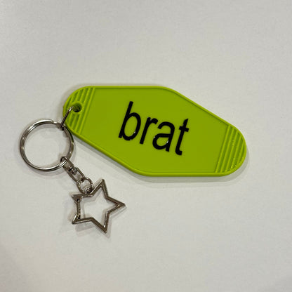 Keychain with a green tag labeled 'brat' and a star charm on a white background
