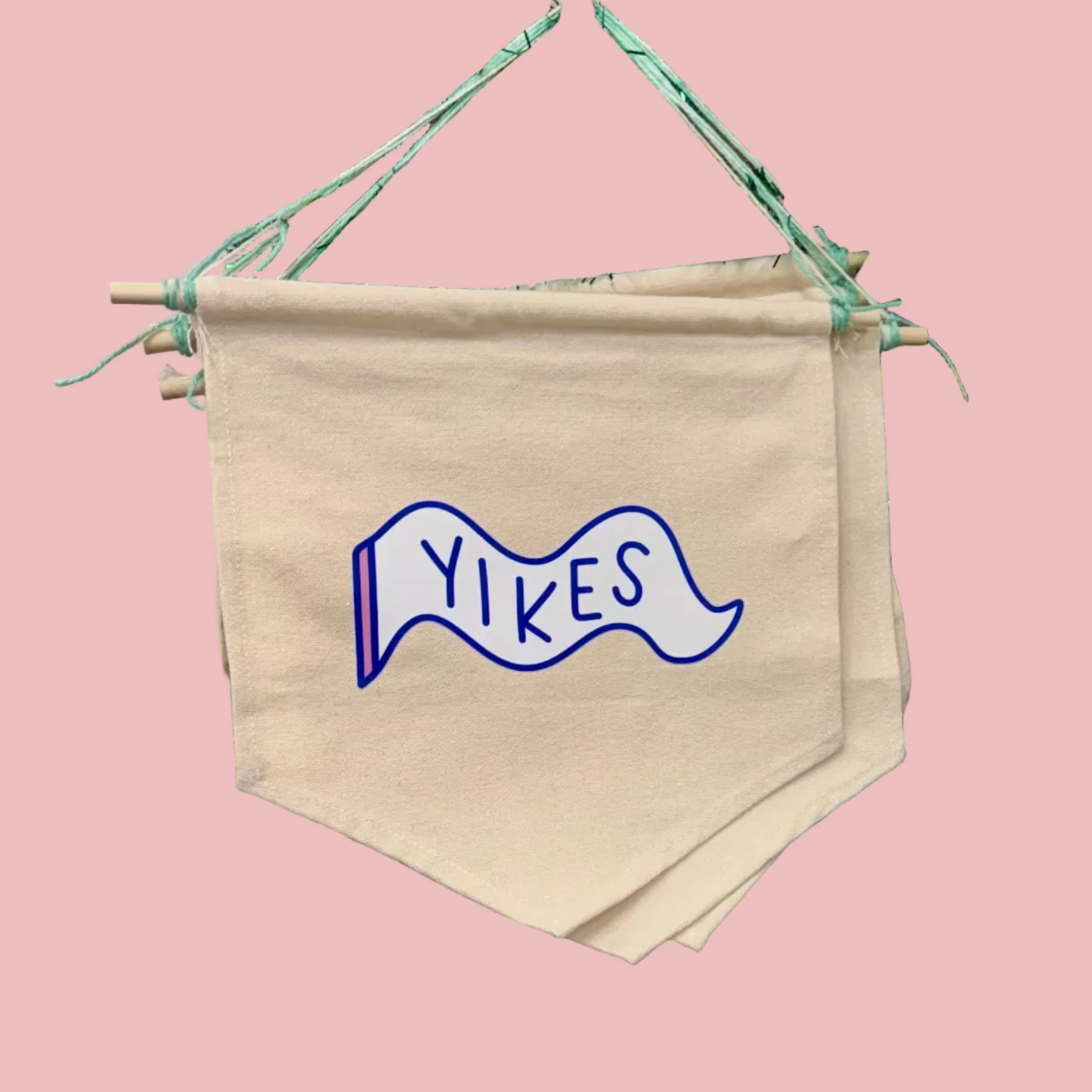 Beige banner with 'Yikes' design hanging on a decorative stand with tinsel.